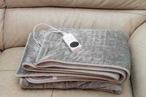 A folded, grey electric blanket on a cream leather sofa