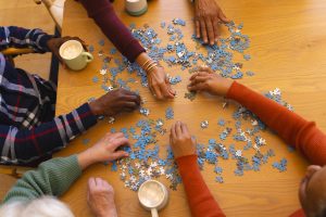 Overhead view of a diverse group of people competing a jigsaw together at a table. 